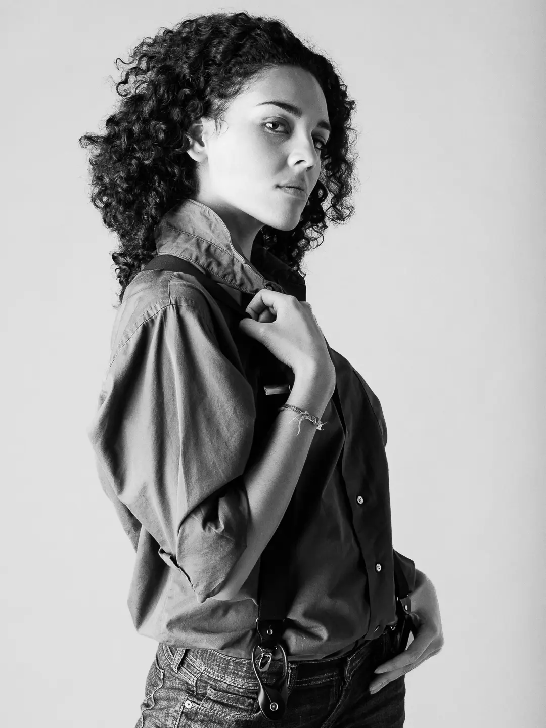 Black and white portrait of Leah wearing a collared shirt and suspenders.