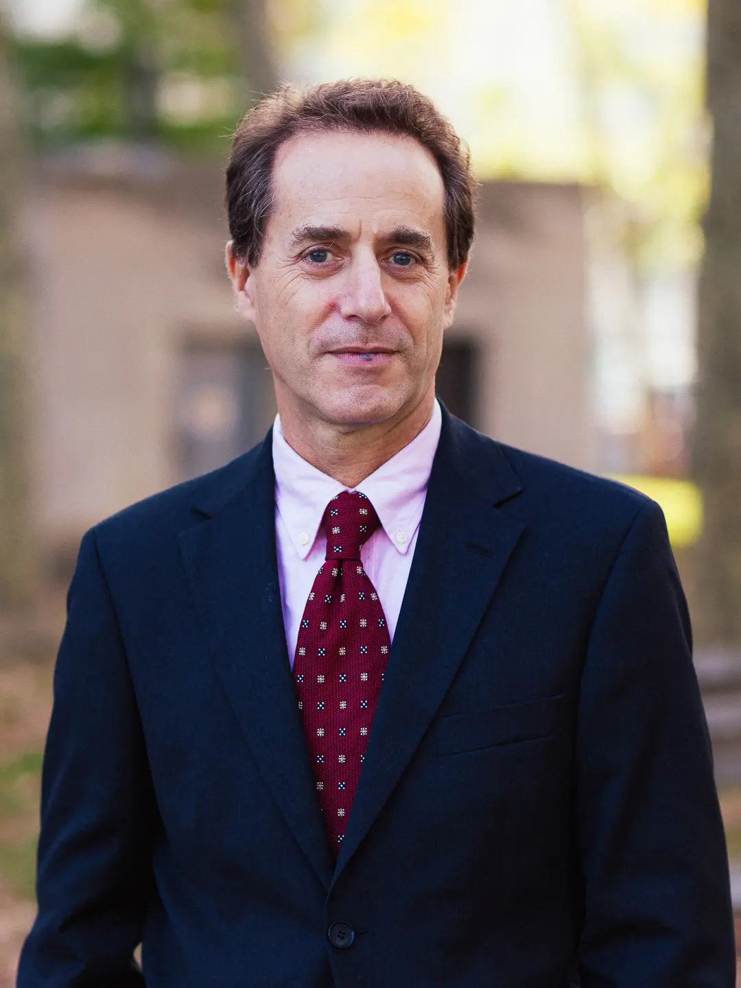 Economist Andrew S. Caplin, in a suit standing outside with blurred trees in the background.