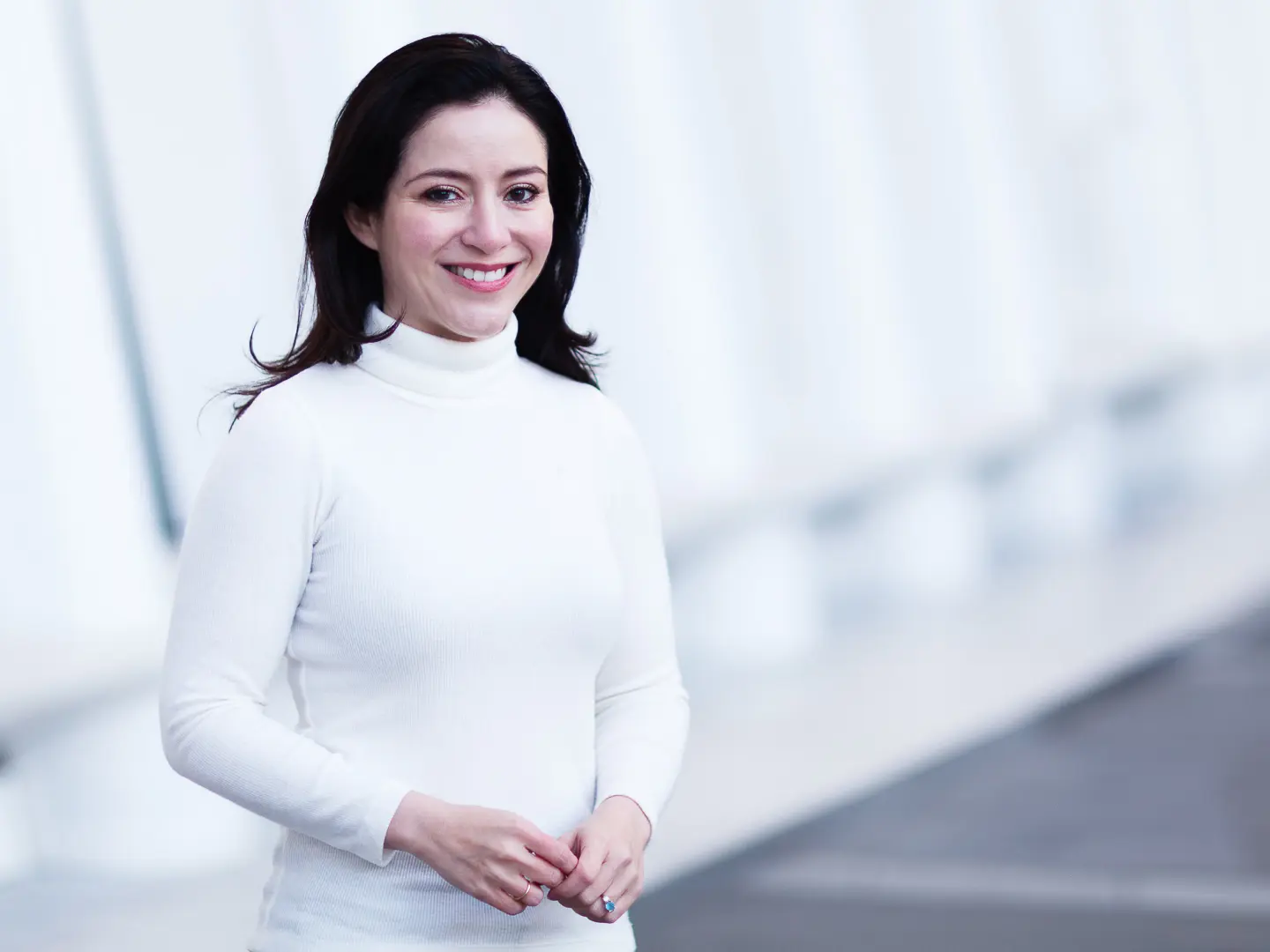 Carmen Segarra in a white turtleneck standing infront of the Oculus at World Trade Center.